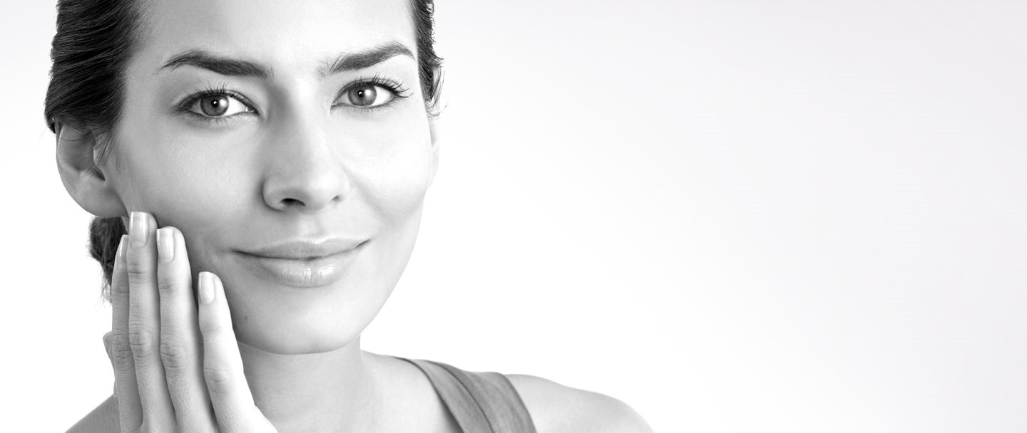 Жінка середнього віку торкається рукою своєї правої щоки