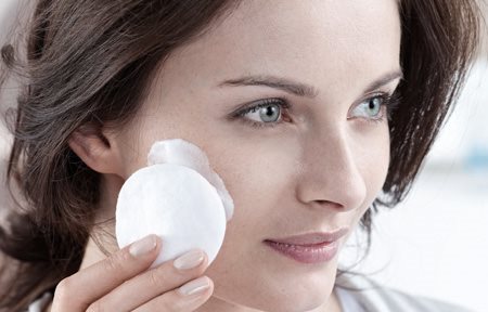 Жінка очищає своє обличчя за допомогою ватного диска