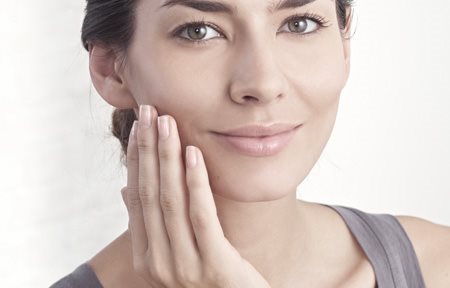 Жінка наносить крем на обличчя