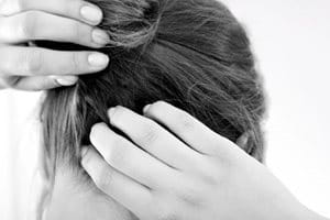 Жінка чухає  шкіру голови, що свербить